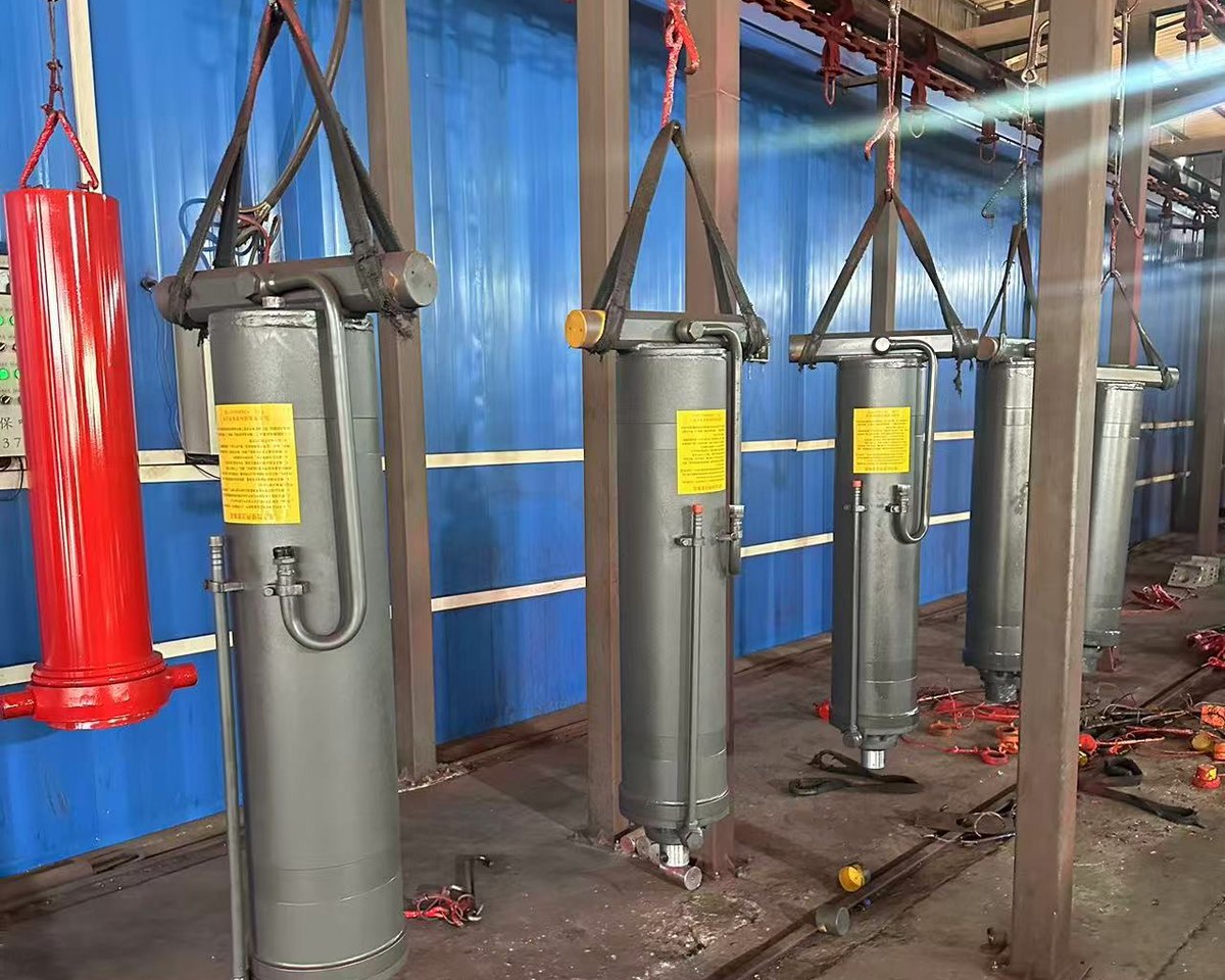 Painted lift cylinders suspended on the overhead conveyor in the workshop